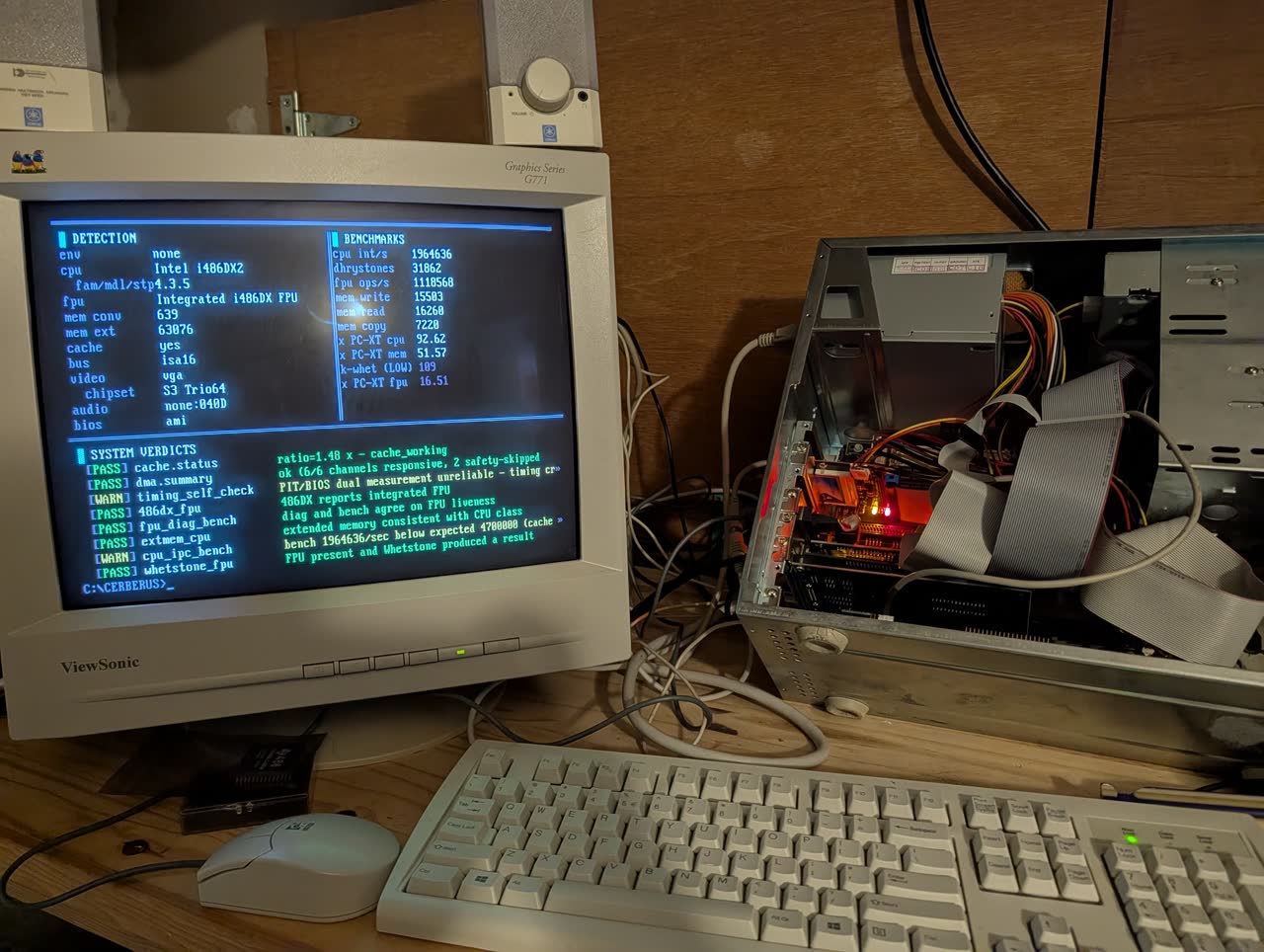 Photograph: CERBERUS v0.4.0 three-pane UI on a ViewSonic CRT monitor, with the open BEK-V409 486 case visible to the right. Red LED glows inside the case.